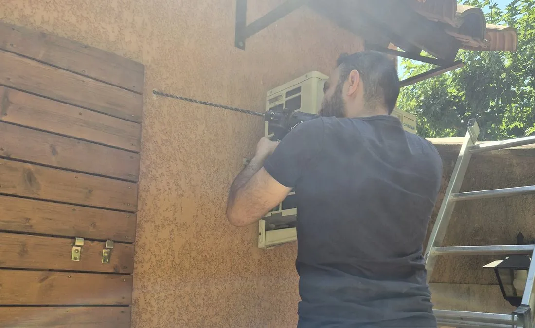Santiago Anton fixant une unité extérieure sur un chantier à Gardanne